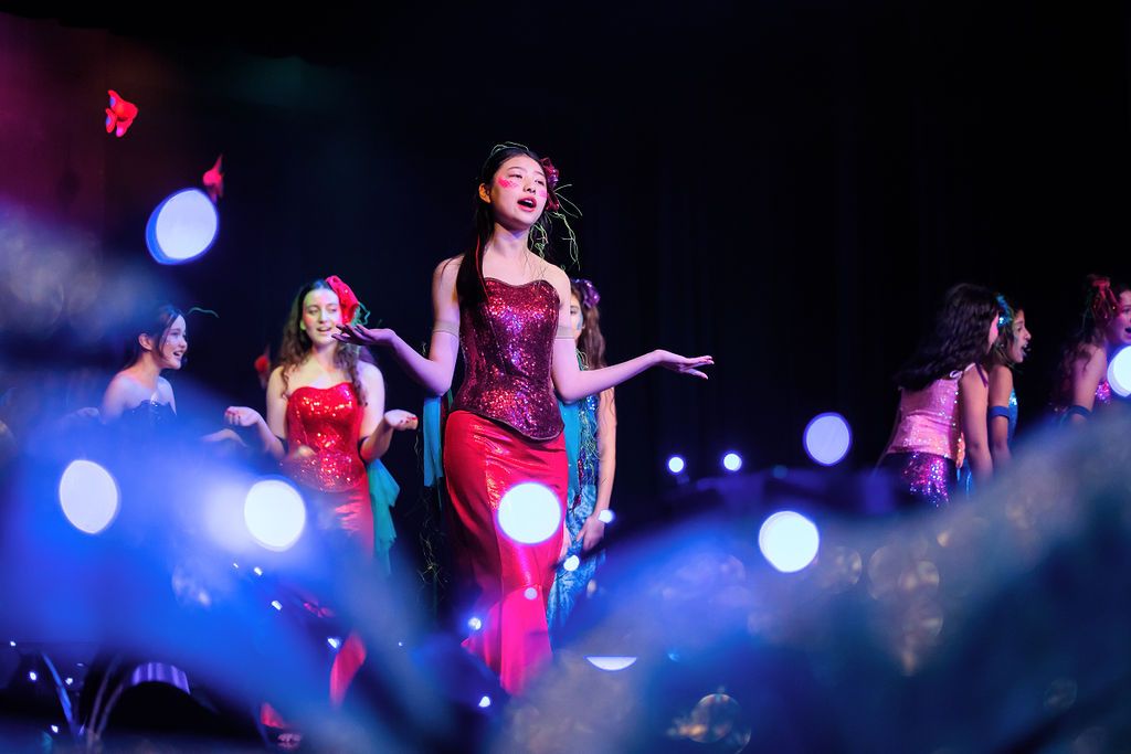 Stage performance with dramatic lighting and performers in red costumes.