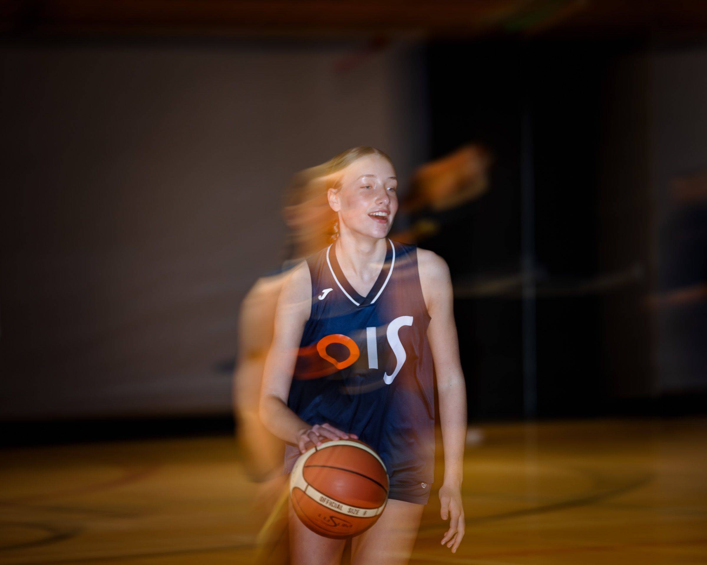 A basketball player in a navy uniform dribbles down the court during an intense game.