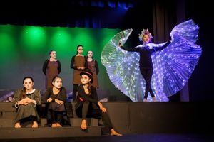 Dance performance on stage with dramatic lighting featuring blue and green effects.