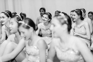 A black and white photo captures dancers in sparkly costumes sharing an emotional moment backstage.