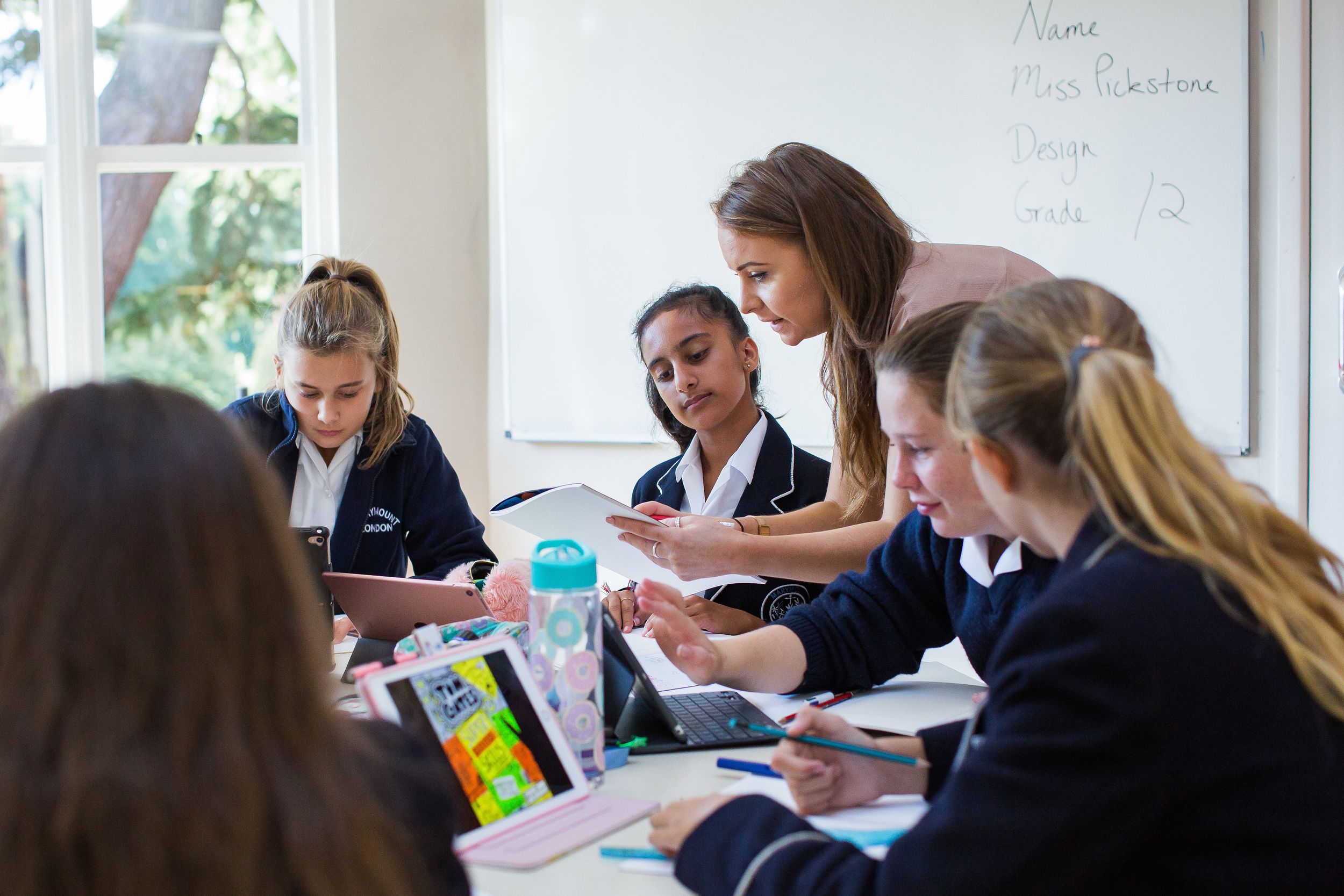Students working together at desks in a bright modern classroom with large windows.