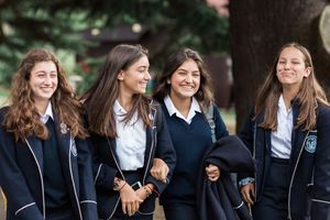 Students in matching school uniforms share a lighthearted moment outdoors.