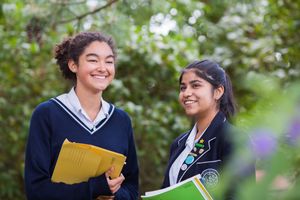 Students in school uniforms studying and socializing outdoors on campus.