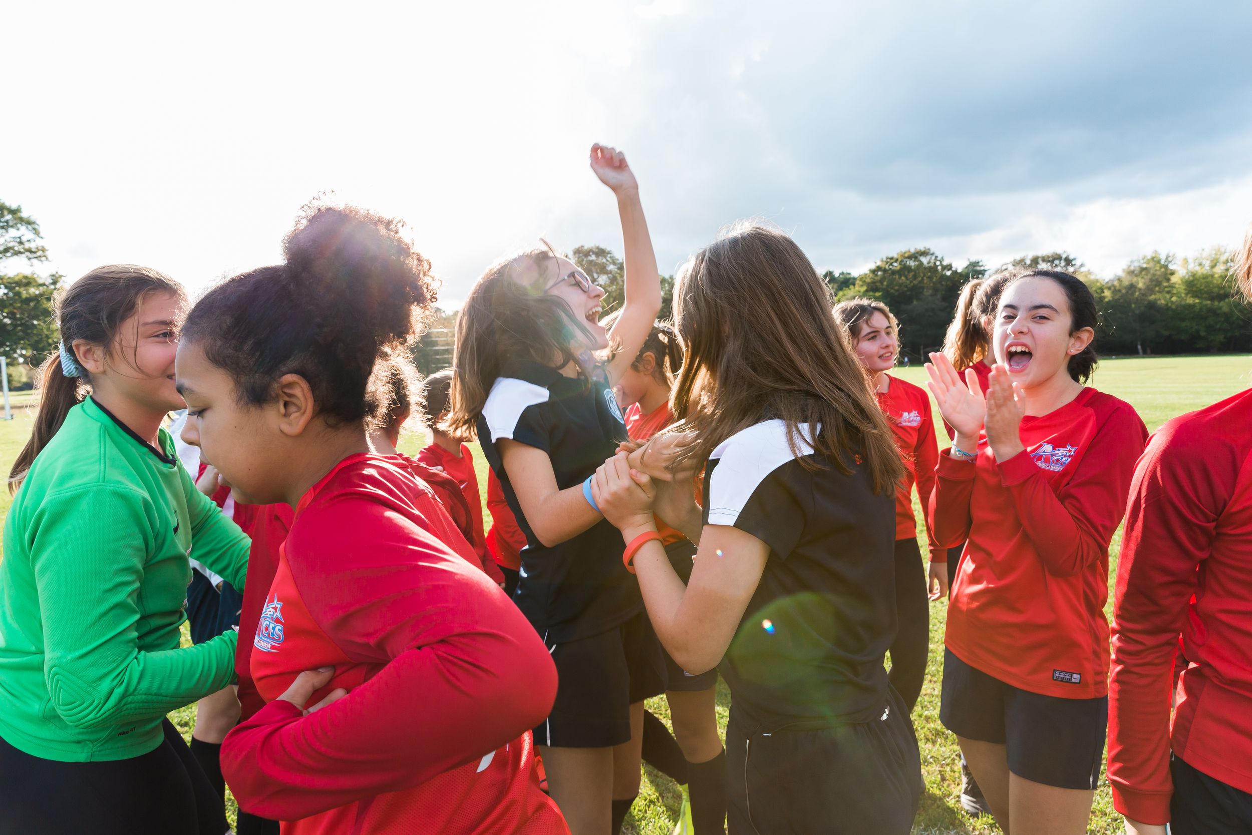 Large group of people in red and green shirts participating in outdoor team building activities.