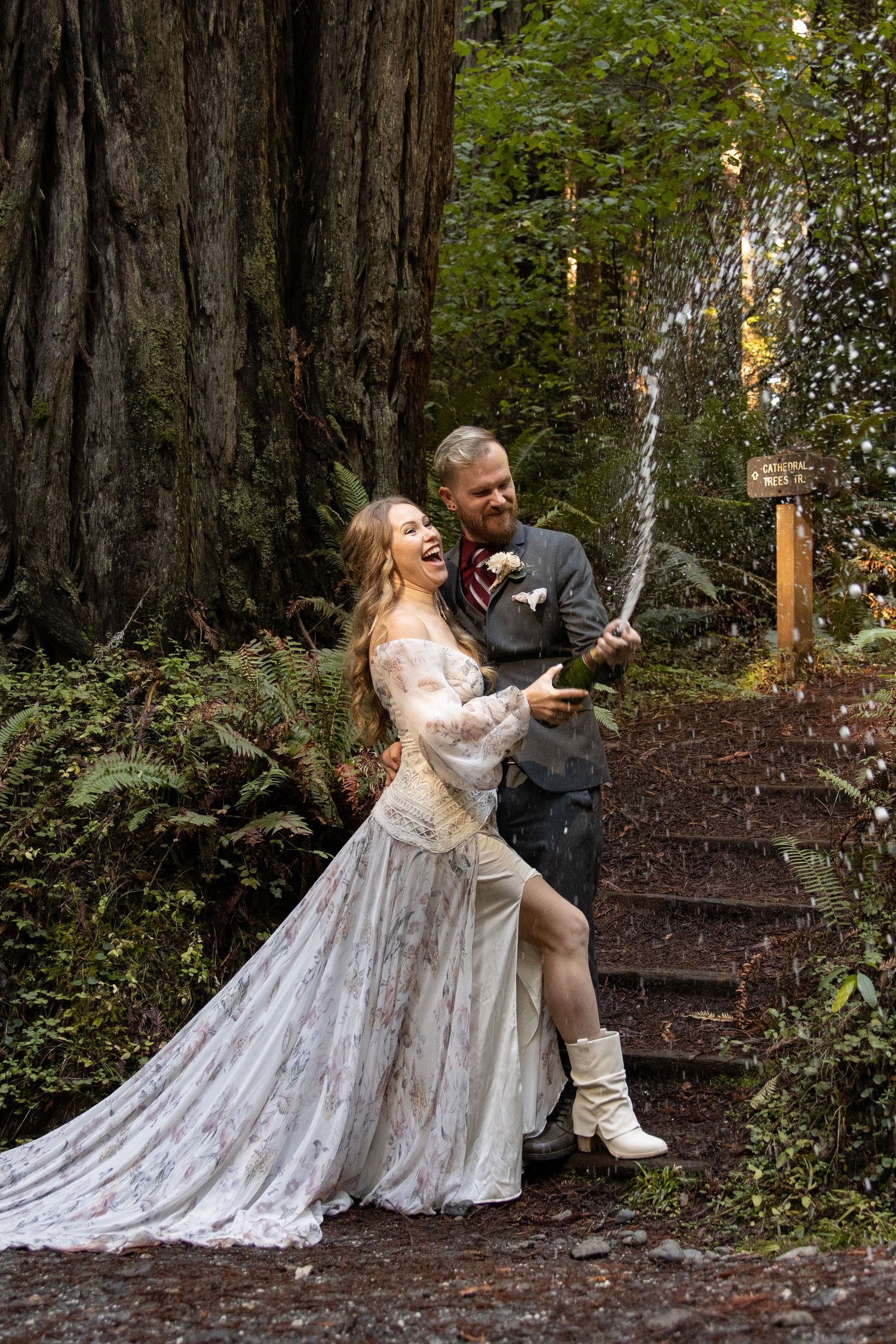 Joyful bride and groom celebrating with champagne spray among towering redwood trees at forest wedding. PNW elopement Photographer.