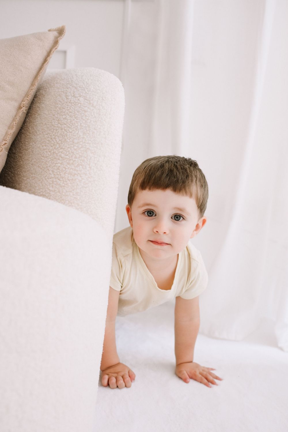Child crawling and playing in bright white minimalist space.