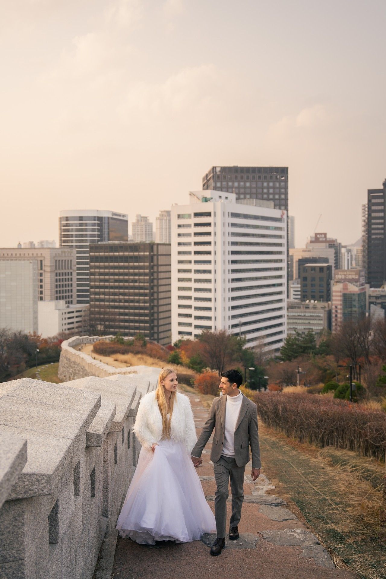 A series of wedding photos showing couples walking along a scenic rooftop terrace with city views in the background.