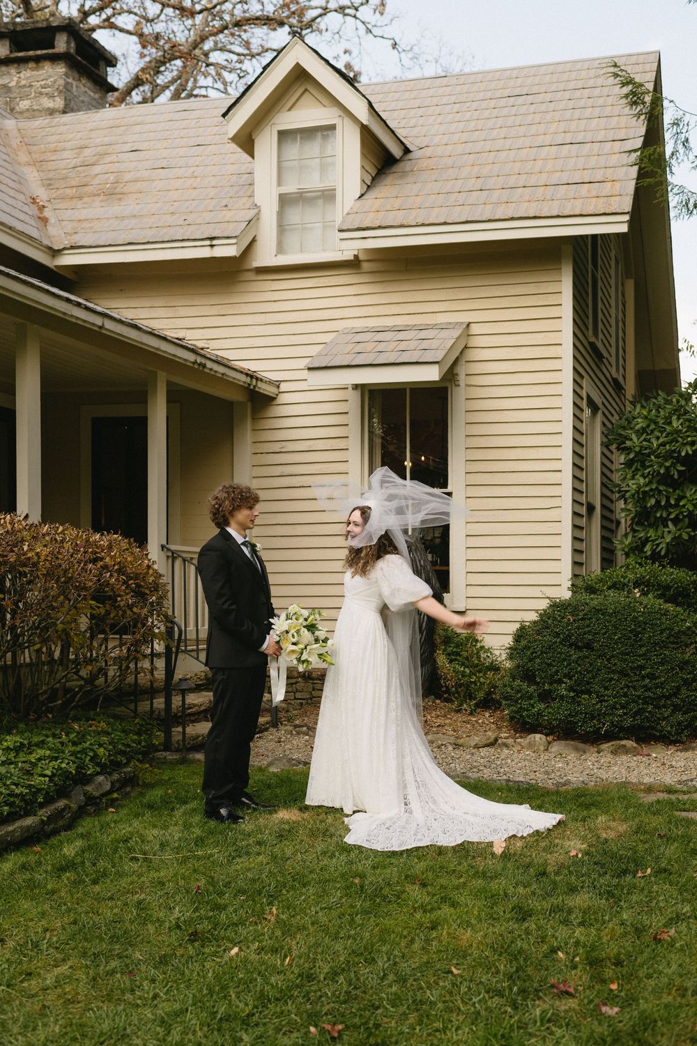 A series of photos showing a first look moment between a couple in wedding attire outside a cream-colored house.