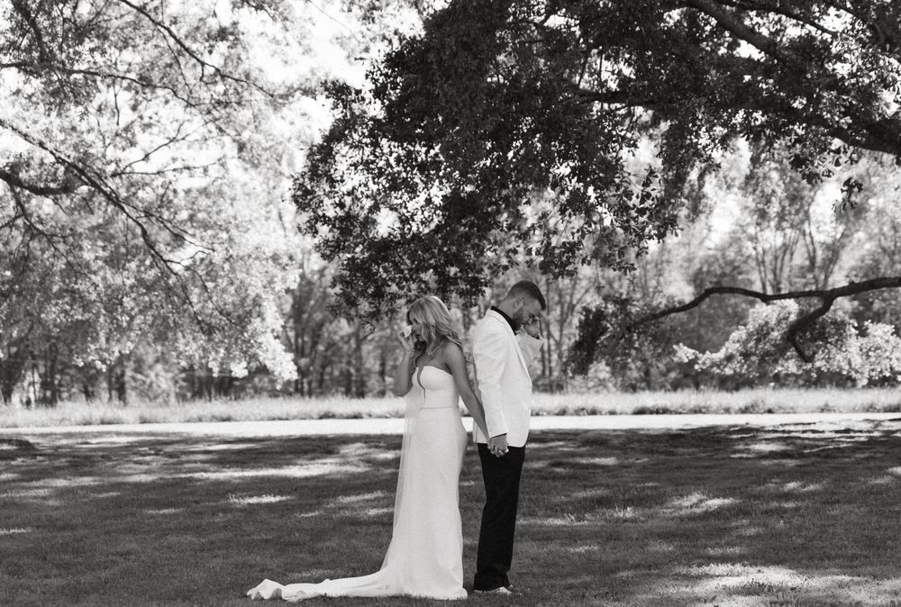 A black and white panoramic photograph shows a peaceful park scene with trees casting shadows on a grassy lawn.