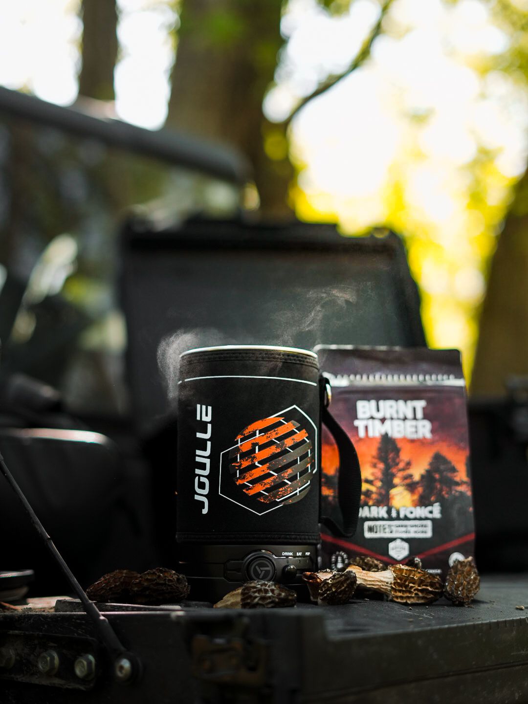 Black and orange branded merchandise containers displayed on a dark surface with natural lighting in background.