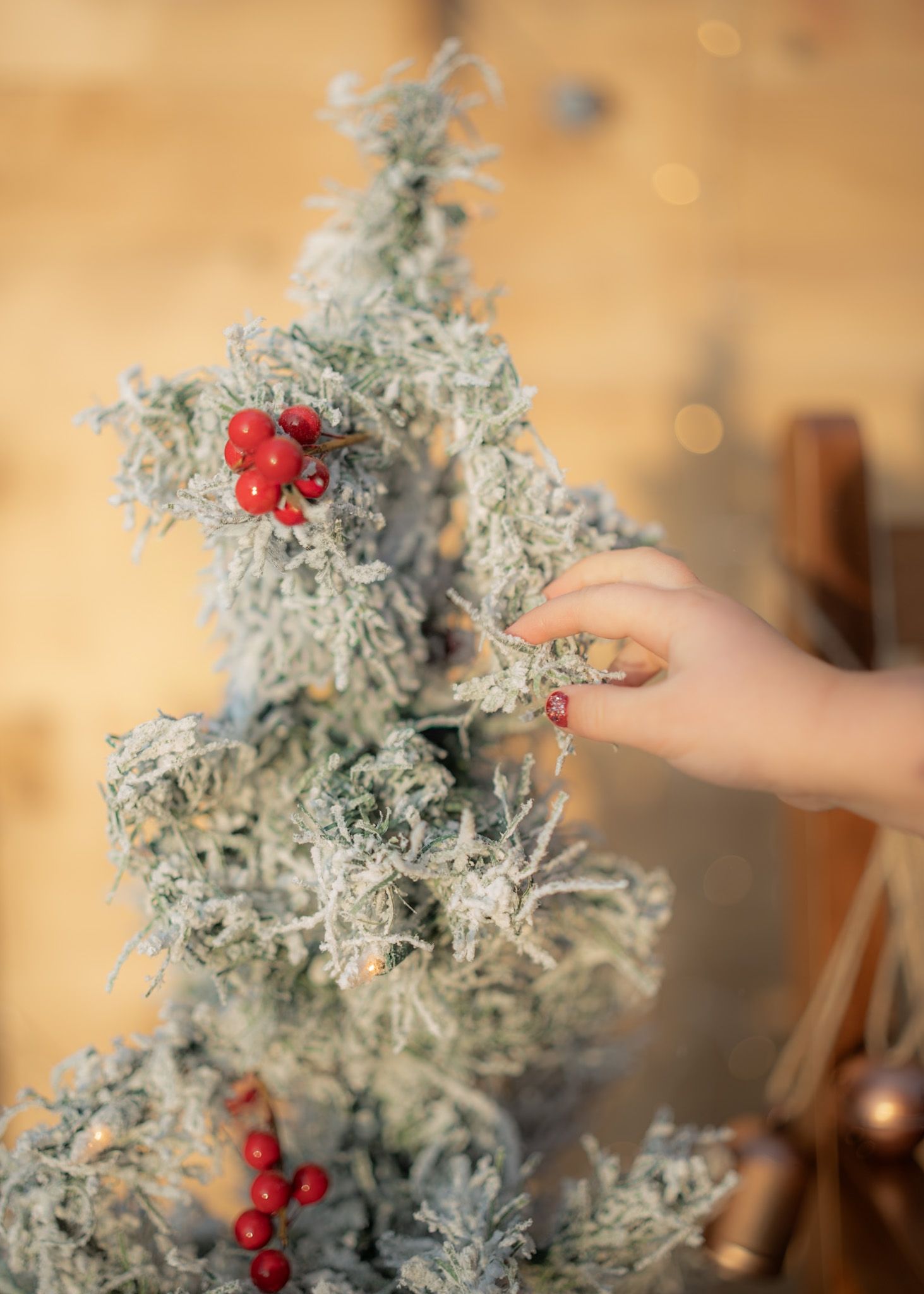 Decorative silver branch with red berries being arranged against warm lighting.