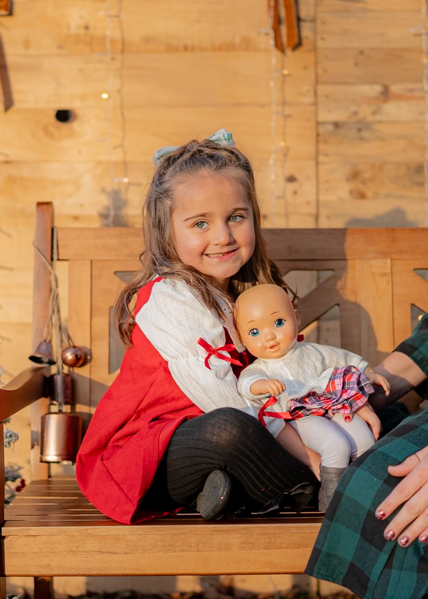 Holiday scene with wooden bench and doll in traditional red and white outfit.