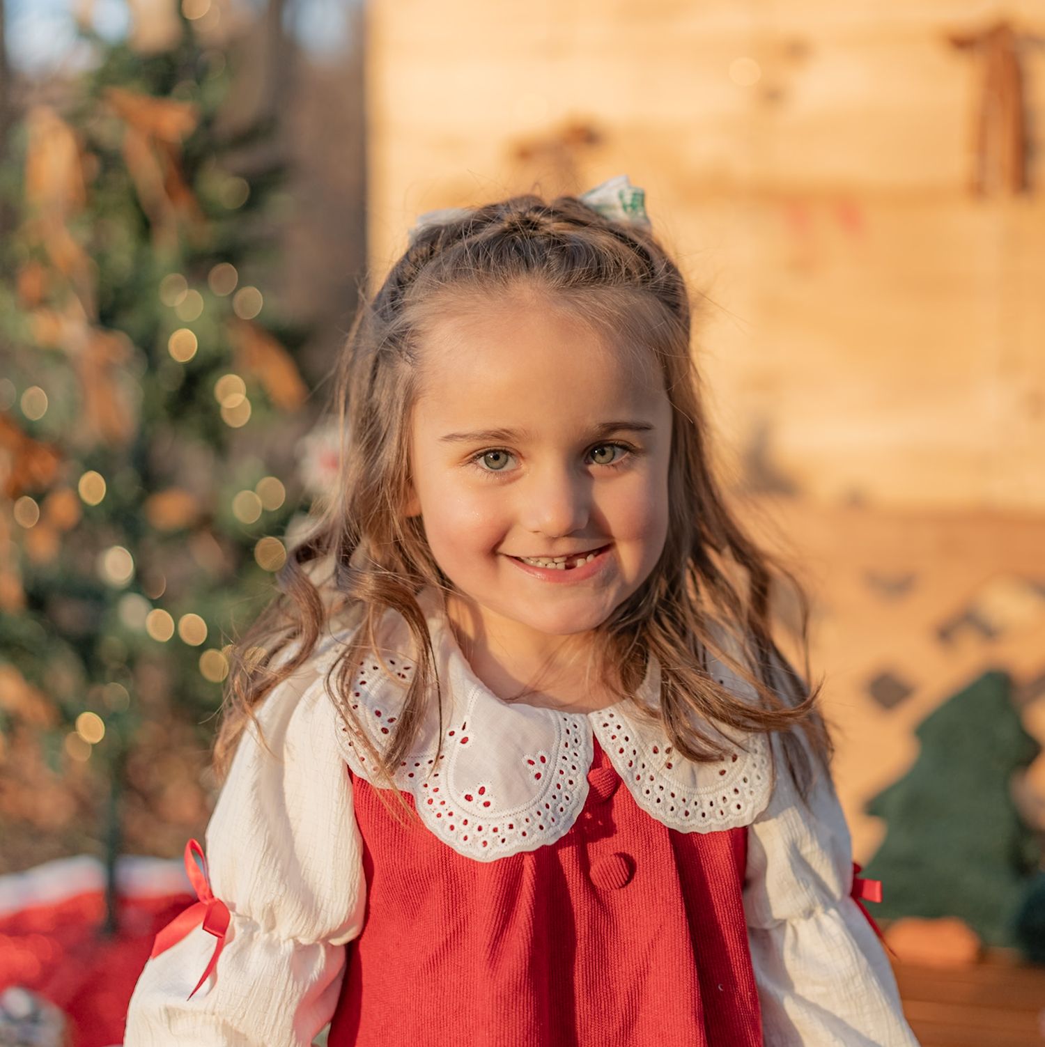 Festive holiday portrait with red dress and white collar against Christmas decorations.