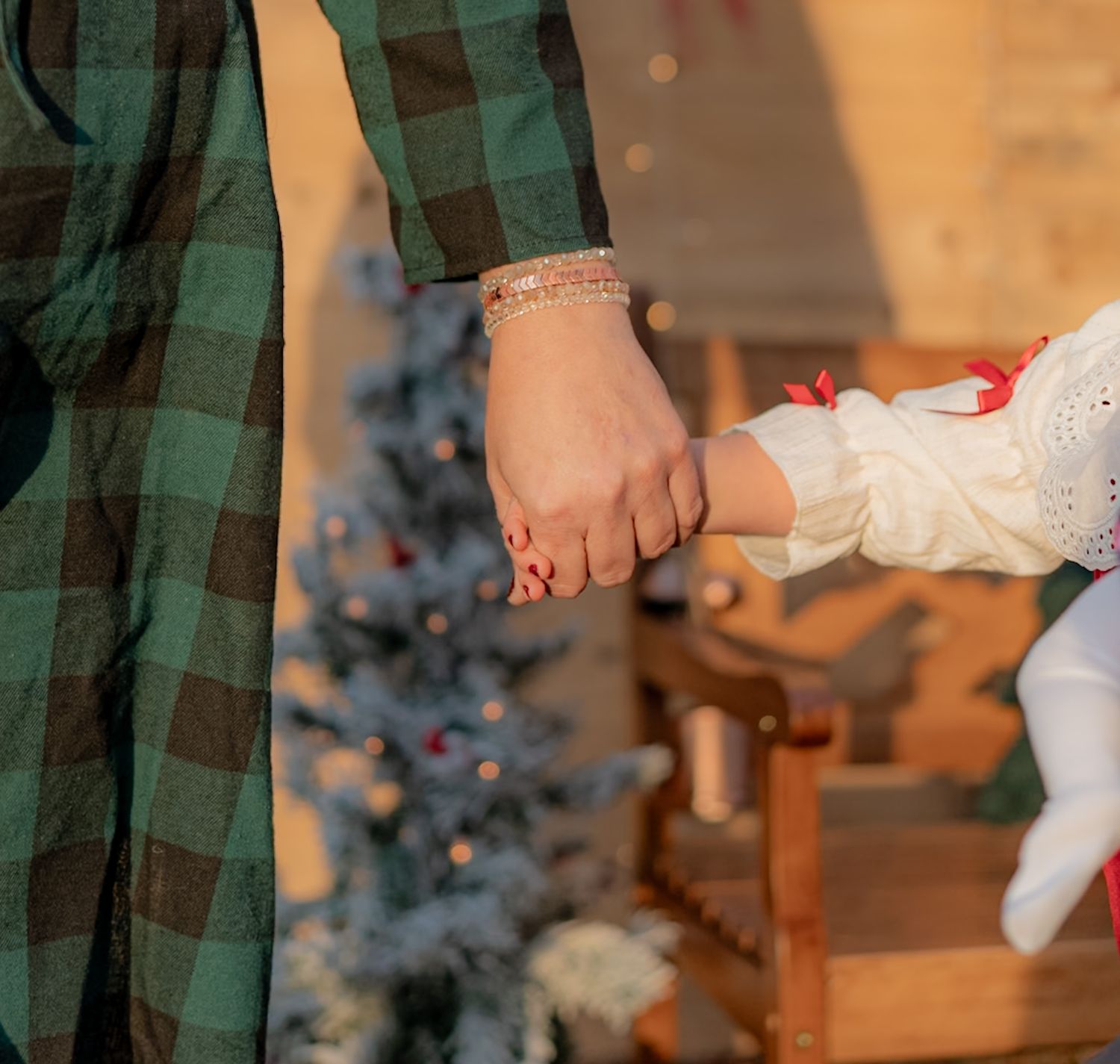 Close-up of green plaid fabric and white lace details in warm holiday lighting.