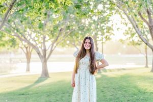 Light and airy portrait of a young teenage girl in a floral dress smiling at Morrison Ranch park in Gilbert, Arizona.