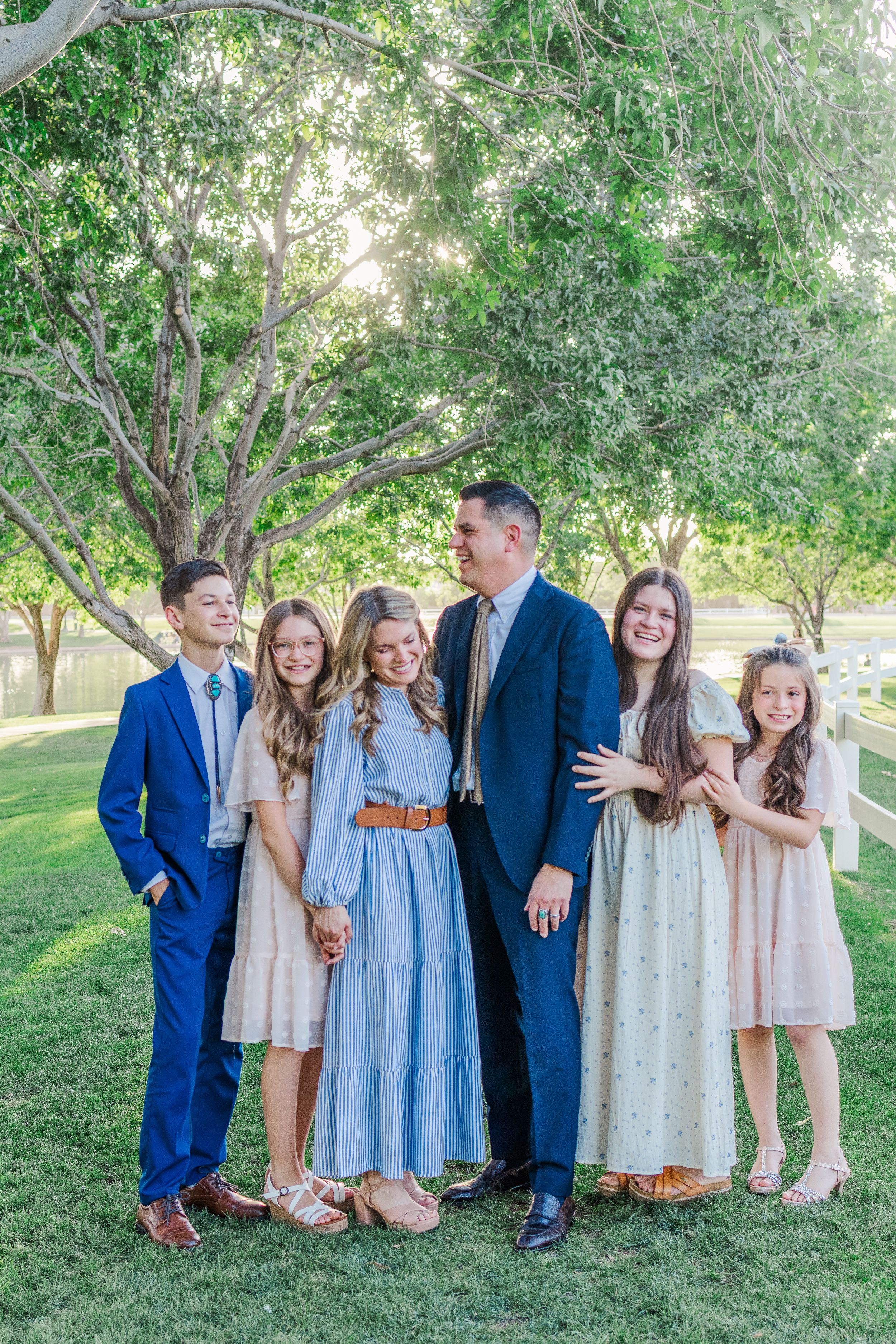 Family of 6 portrait smiling and laughing at one another in a row in Gilbert, Arizona at Morrison Ranch.