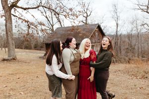 A group of friends laughs together while walking on a wooded path during an autumn photoshoot.