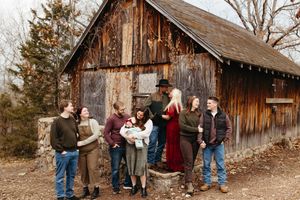 A group of people gathered outside a rustic wooden barn in autumn wearing casual clothing.