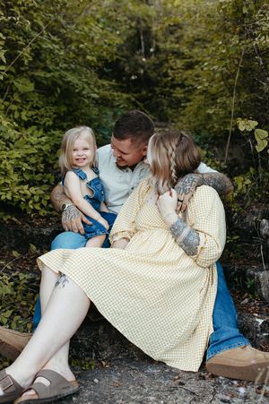 A family sits together on a wooden swing in a lush garden setting, sharing intimate moments and laughter.