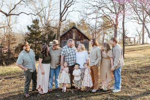 A group of people in casual attire walk together through a wooded outdoor setting during a photo session.