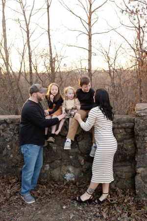 A family enjoys a playful moment together against a rustic stone wall during an outdoor photo session.
