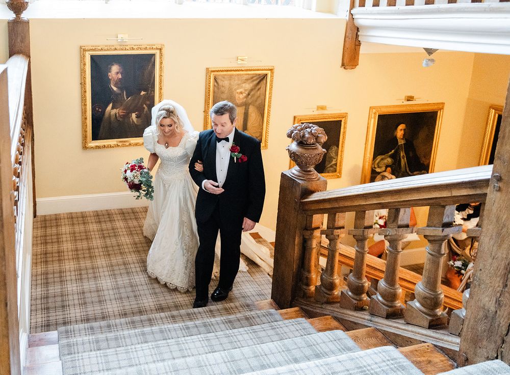Interior view of a carpeted hallway with wooden handrails and framed artwork on beige walls.