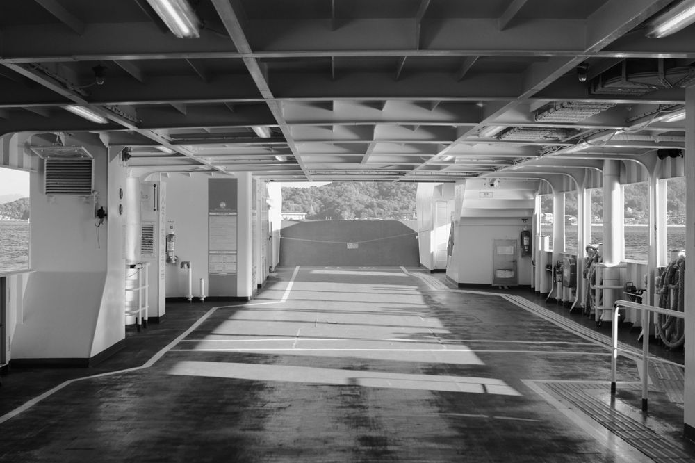Empty indoor parking garage with concrete columns and fluorescent lighting extending into the distance.