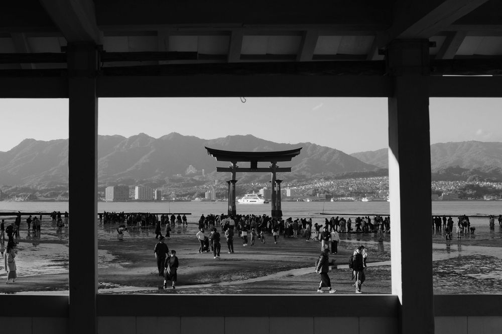 Black and white panoramic view of Itsukushima Shrine's torii gate and coastline in Japan.