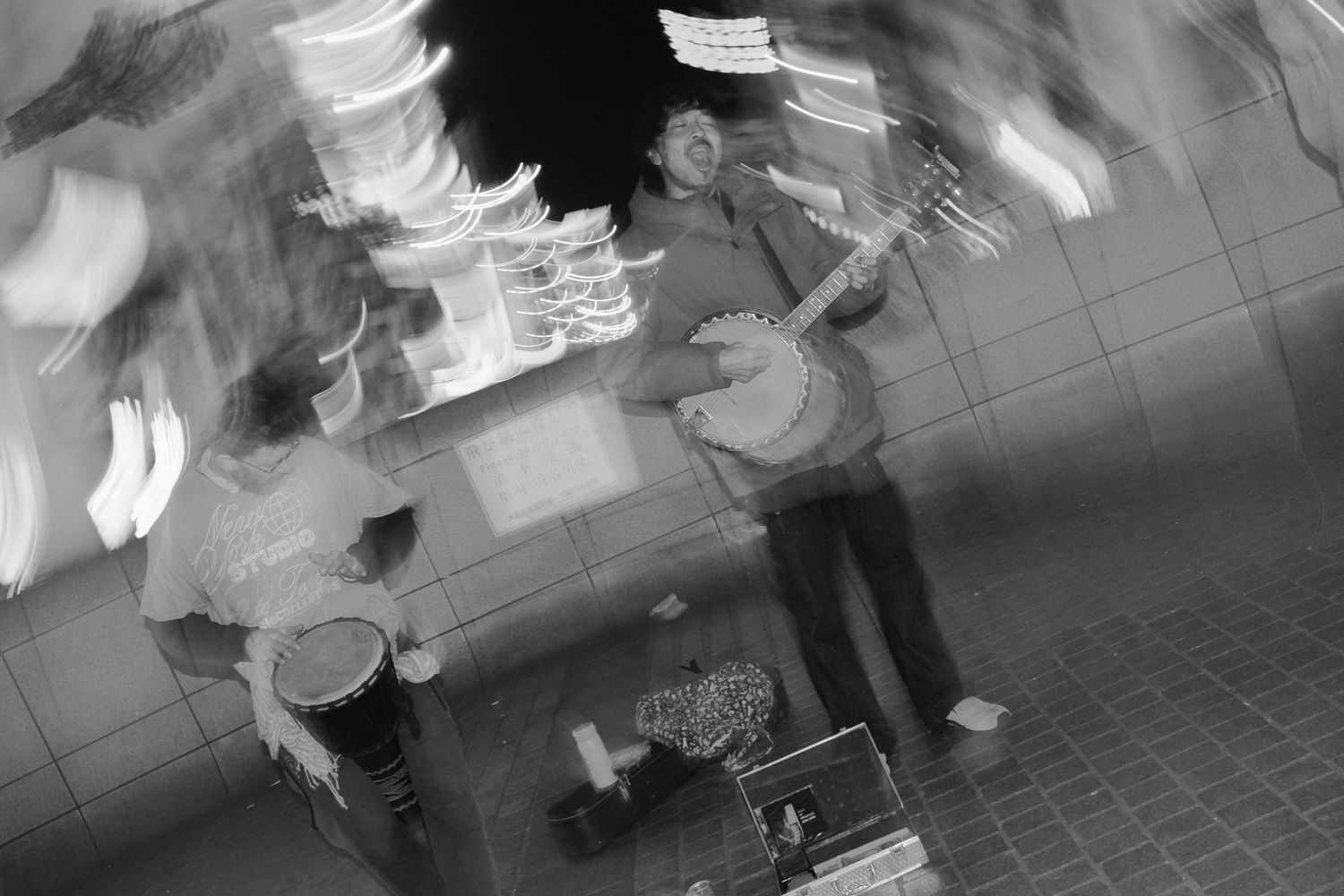 A black and white surveillance camera footage shows people walking through what appears to be a hallway or corridor.