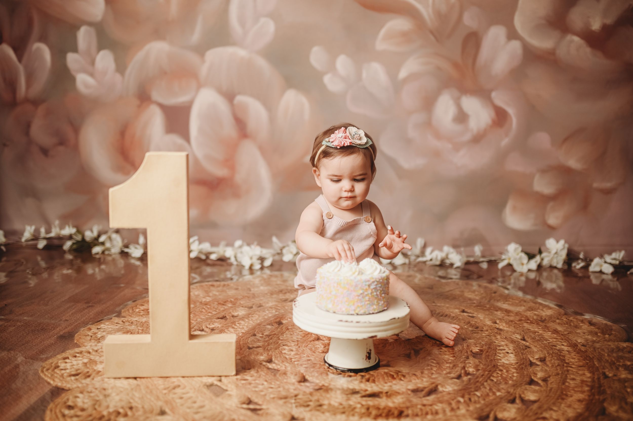 First birthday cake smash photo session with peach and white decorative backdrop.