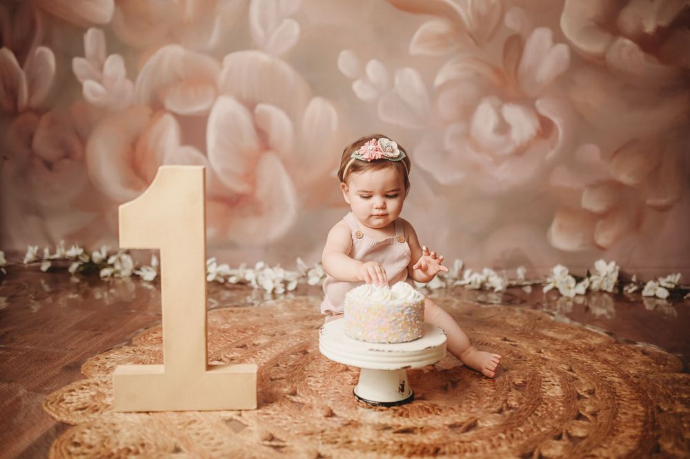 First birthday cake smash photo session with peach and white decorative backdrop.