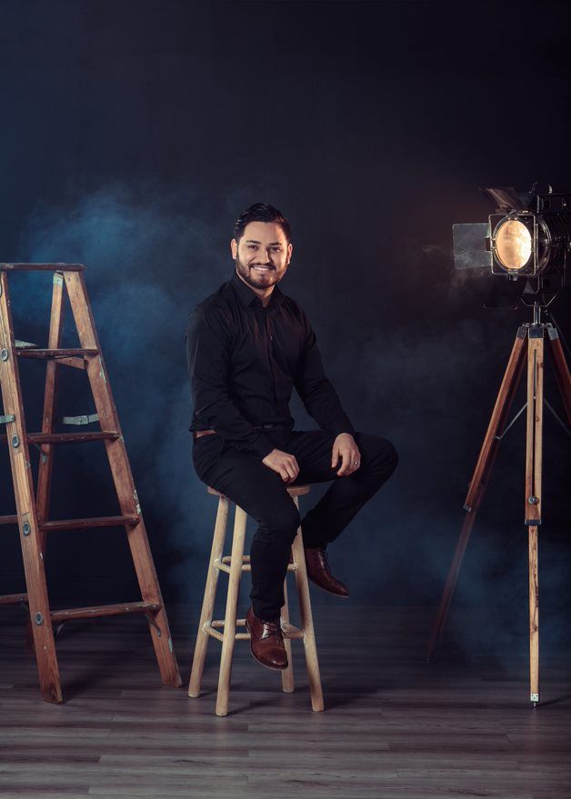 Studio portrait setup with dramatic lighting, smoke effects, vintage ladder and spotlight equipment.