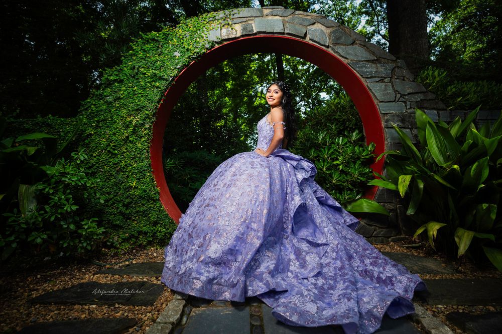 Lavender ballgown with voluminous skirt photographed under a red circular garden arch.