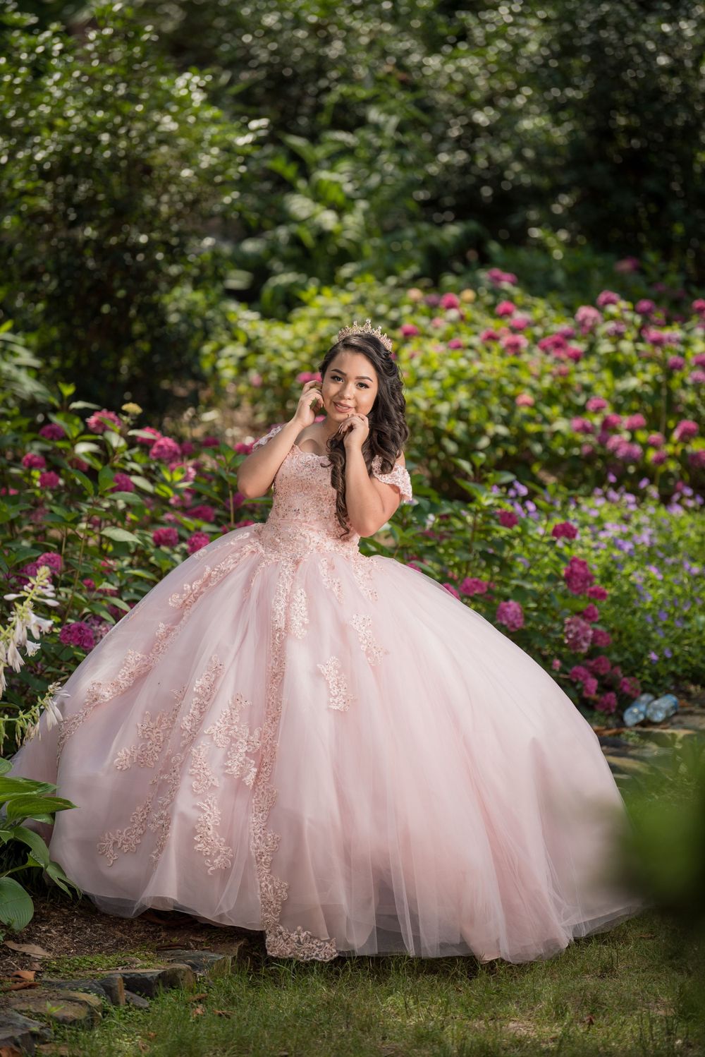 Beautiful pink princess ball gown photographed in blooming garden with pink flowers.