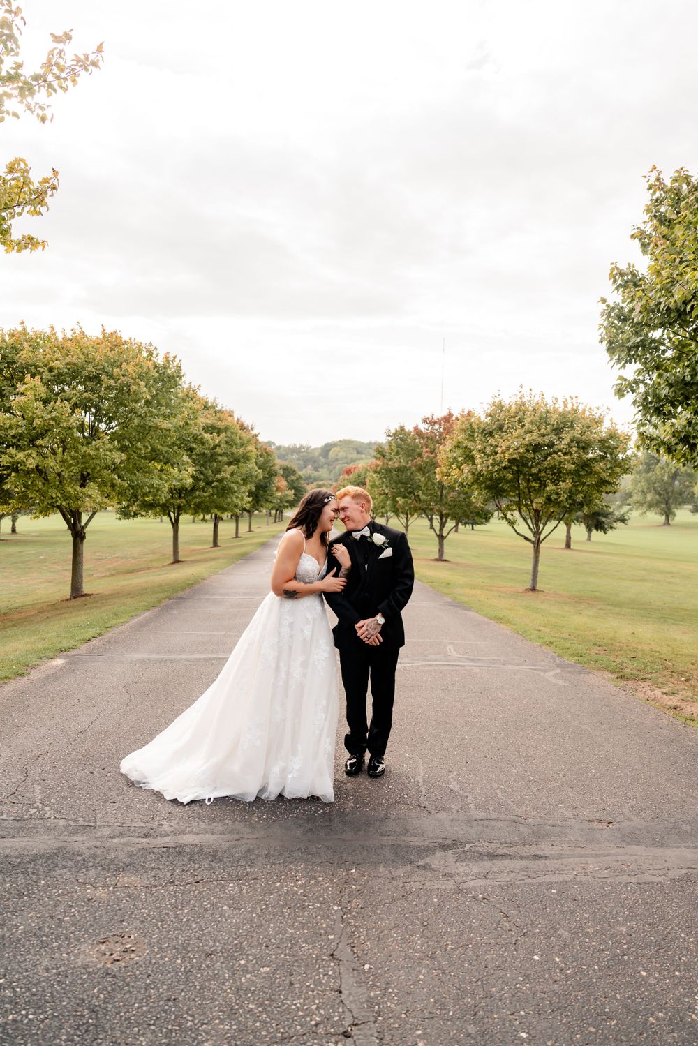 A couple walking together on a tree-lined path during their wedding day.