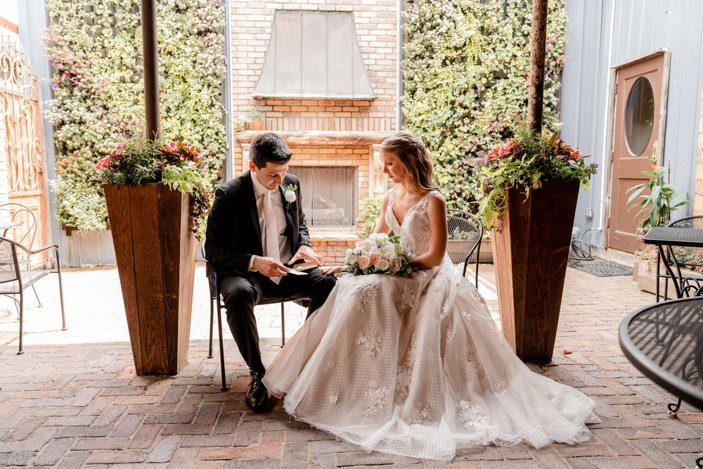 A couple shares an intimate moment seated outdoors surrounded by potted plants.