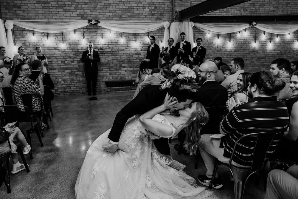 A reception crowd celebrates as a couple shares a romantic dip on the dance floor.