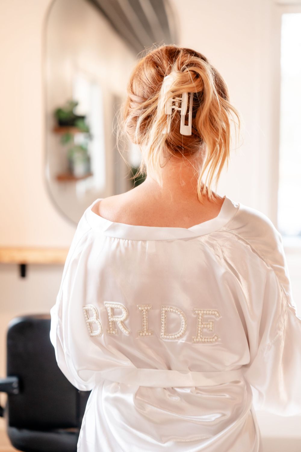 Back view of woman wearing white satin robe with 'BRIDE' text embroidered.