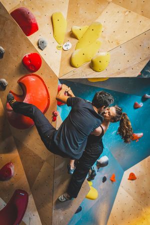 Rock climbers practicing bouldering techniques on an angled indoor wall with multicolored climbing holds the Bouldering Project in DC