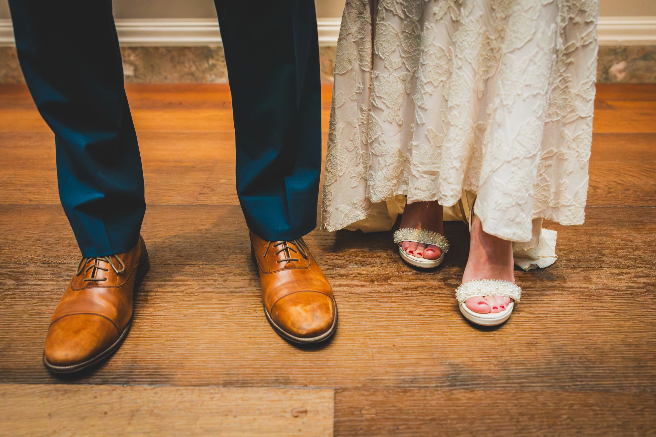 couple's feet close-up showing groom's brown dress shoes and bride's pink sandals on hardwood floor National Gallery Of Art in DC