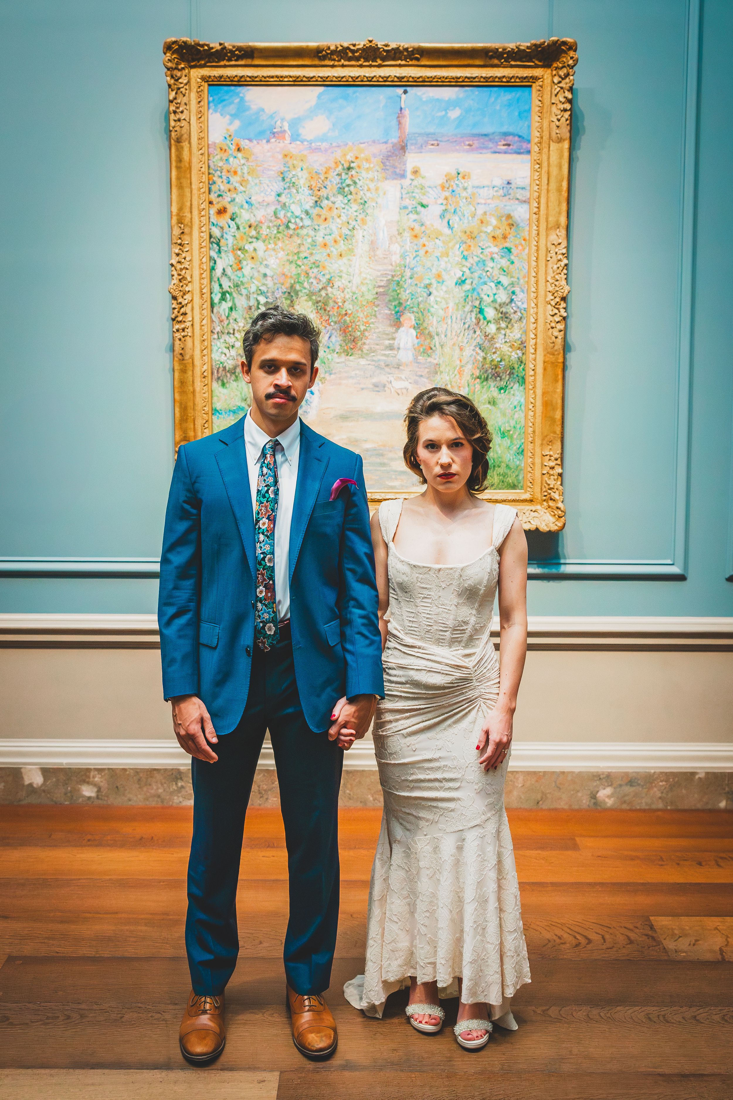 Couple in wedding attire pose together against turquoise wall with framed artwork in art gallery setting National Gallery Of Art in DC