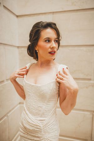 Sequence showing woman adjusting shoulder straps of cream colored formal gown in delicate vintage style photography.