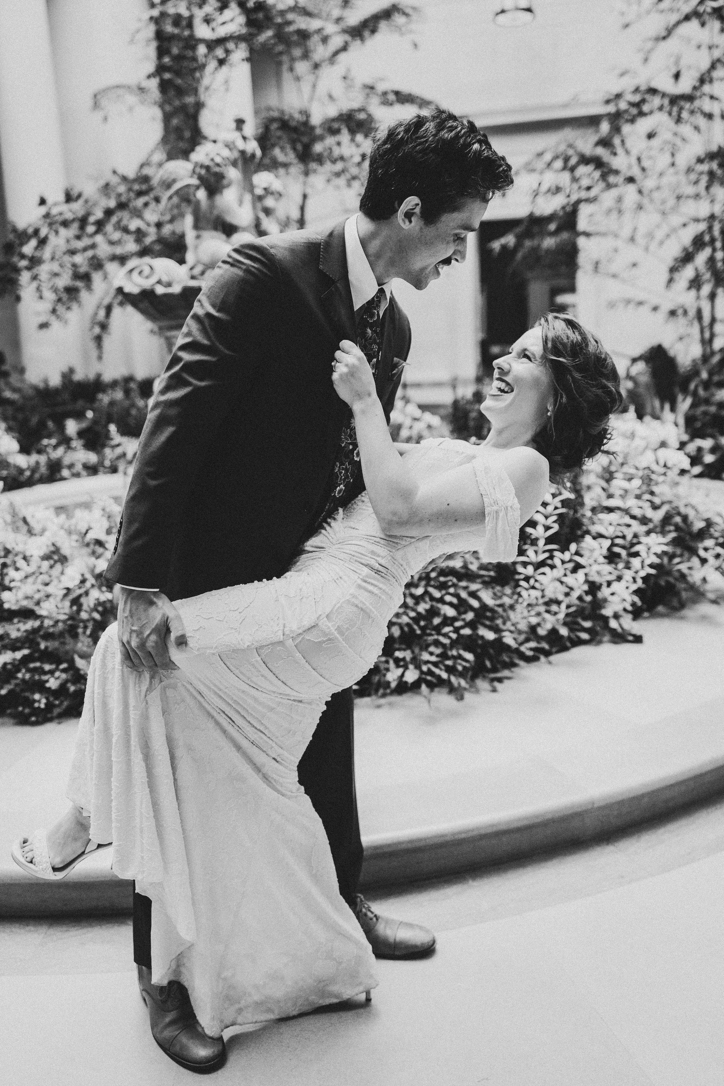 A romantic black and white photo of a couple dancing together, with the woman being dipped in an elegant white dress.