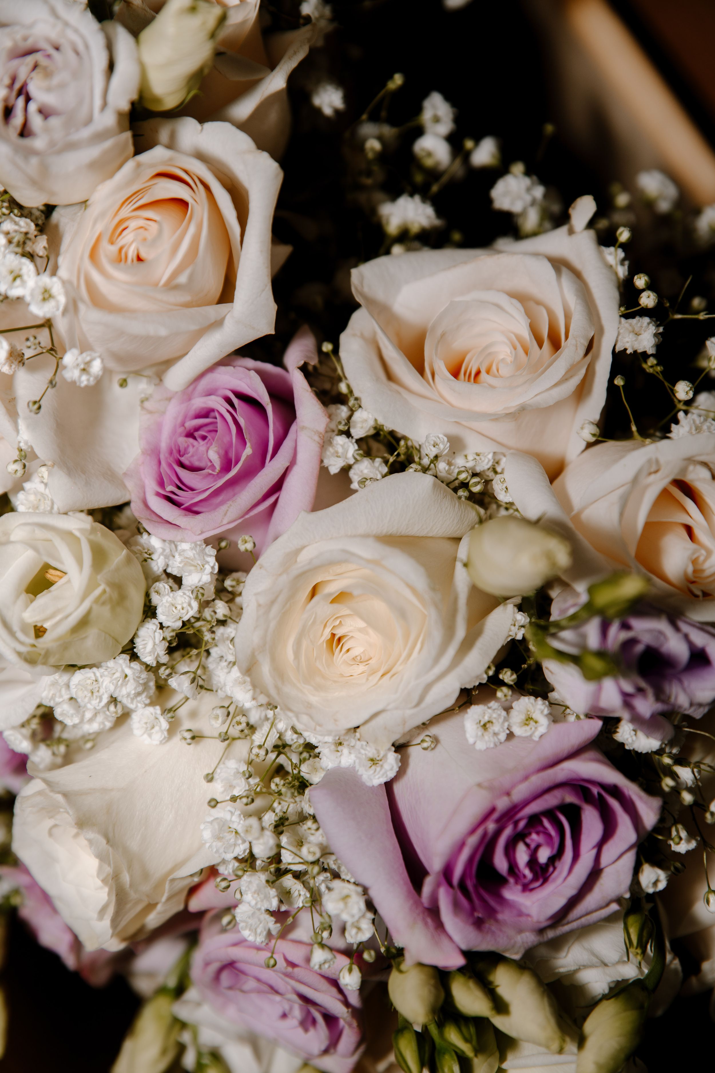 Close-up of a romantic wedding bouquet with cream-colored and lavender roses complemented by delicate baby's breath.