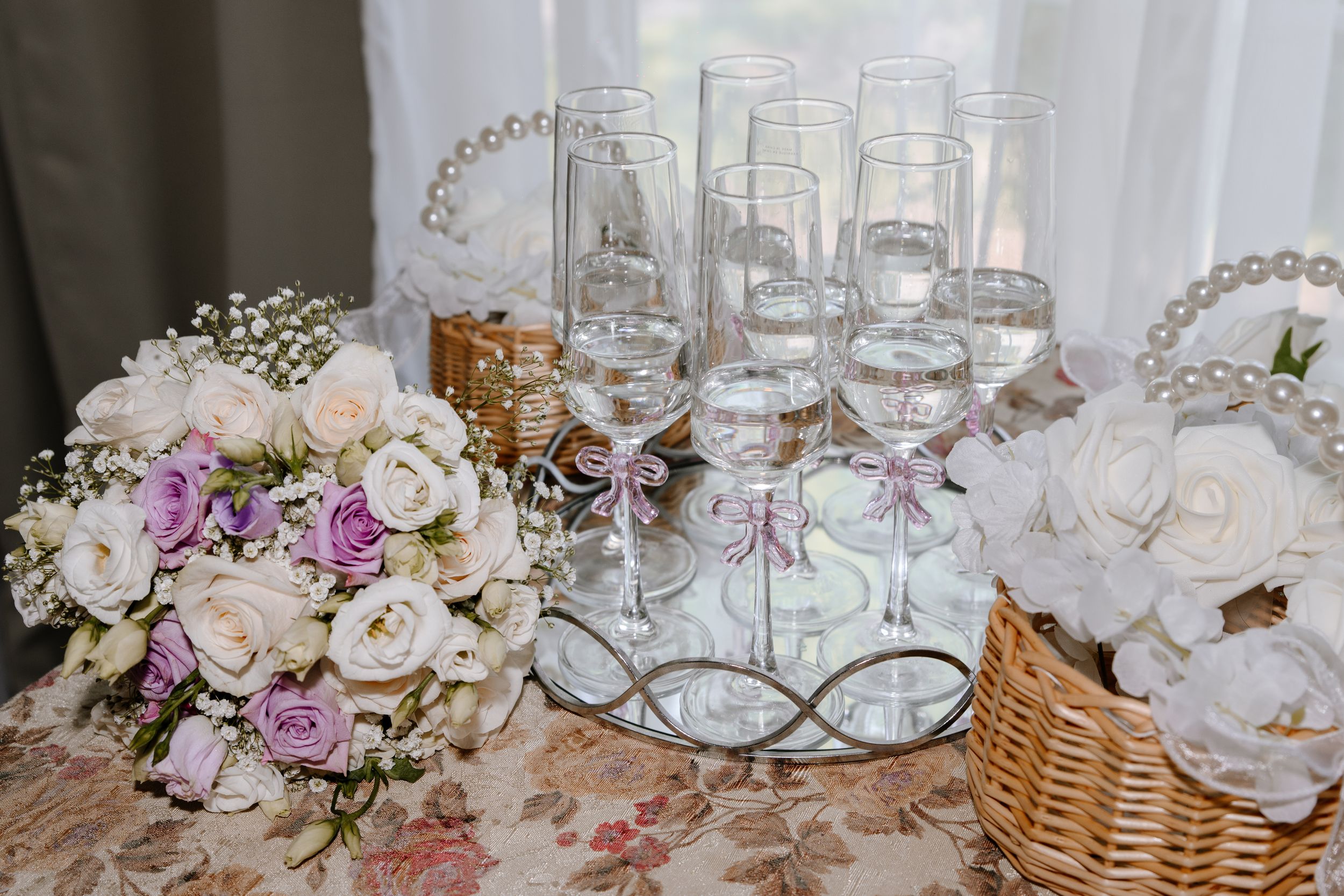 Elegant wedding reception table settings with crystal glassware, floral arrangements, and woven basket decor.