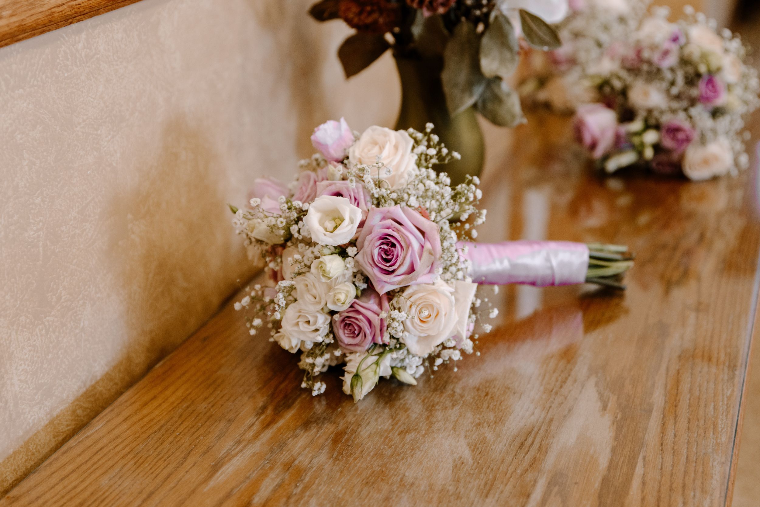 A romantic bridal bouquet featuring pink and cream roses with baby's breath tied together with white ribbon.