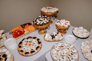 An elegant dessert table with assorted cupcakes, pastries, cookies and sweets arranged on gold decorative stands.