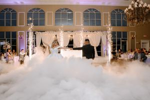 Long white wedding dresses displayed on hangers in a bridal boutique with elegant chandelier lighting.