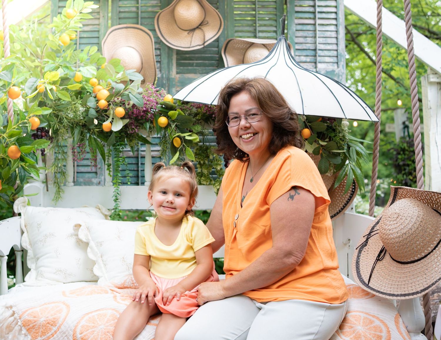 Summer garden scene with straw hats and cheerful orange accents on white furniture.