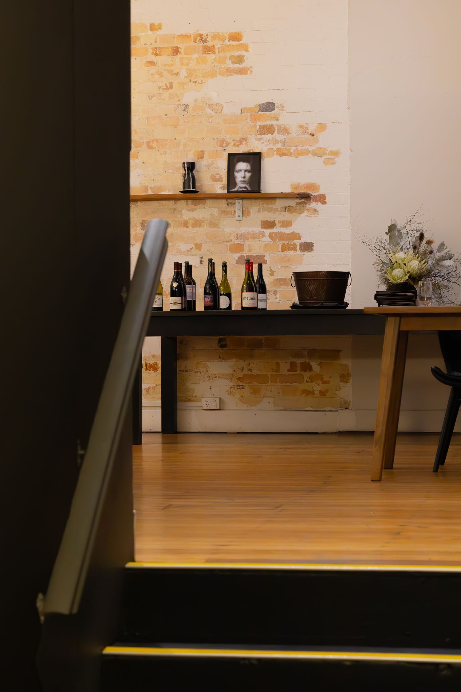 Moody restaurant interior features exposed brick walls, wooden furniture, and ambient lighting creating a cozy atmosphere.